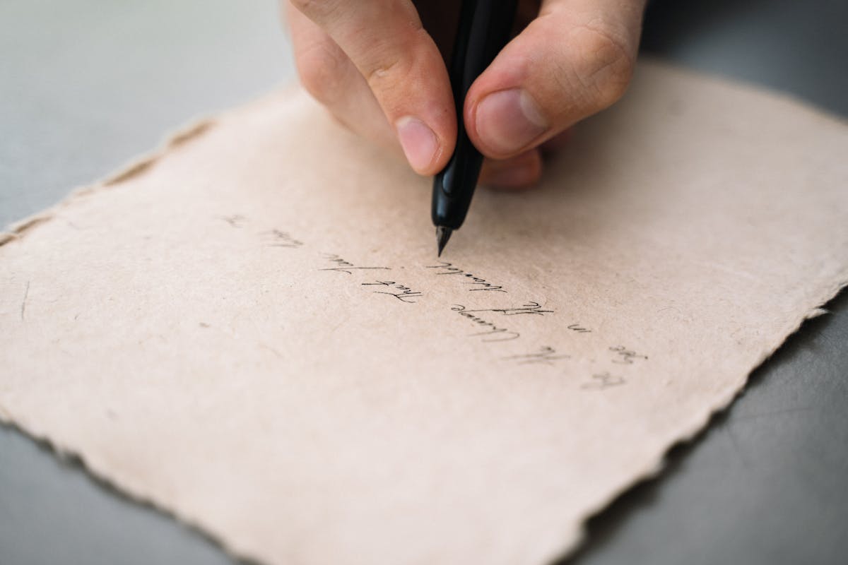 A handwritten letter on aged paper beside a pen